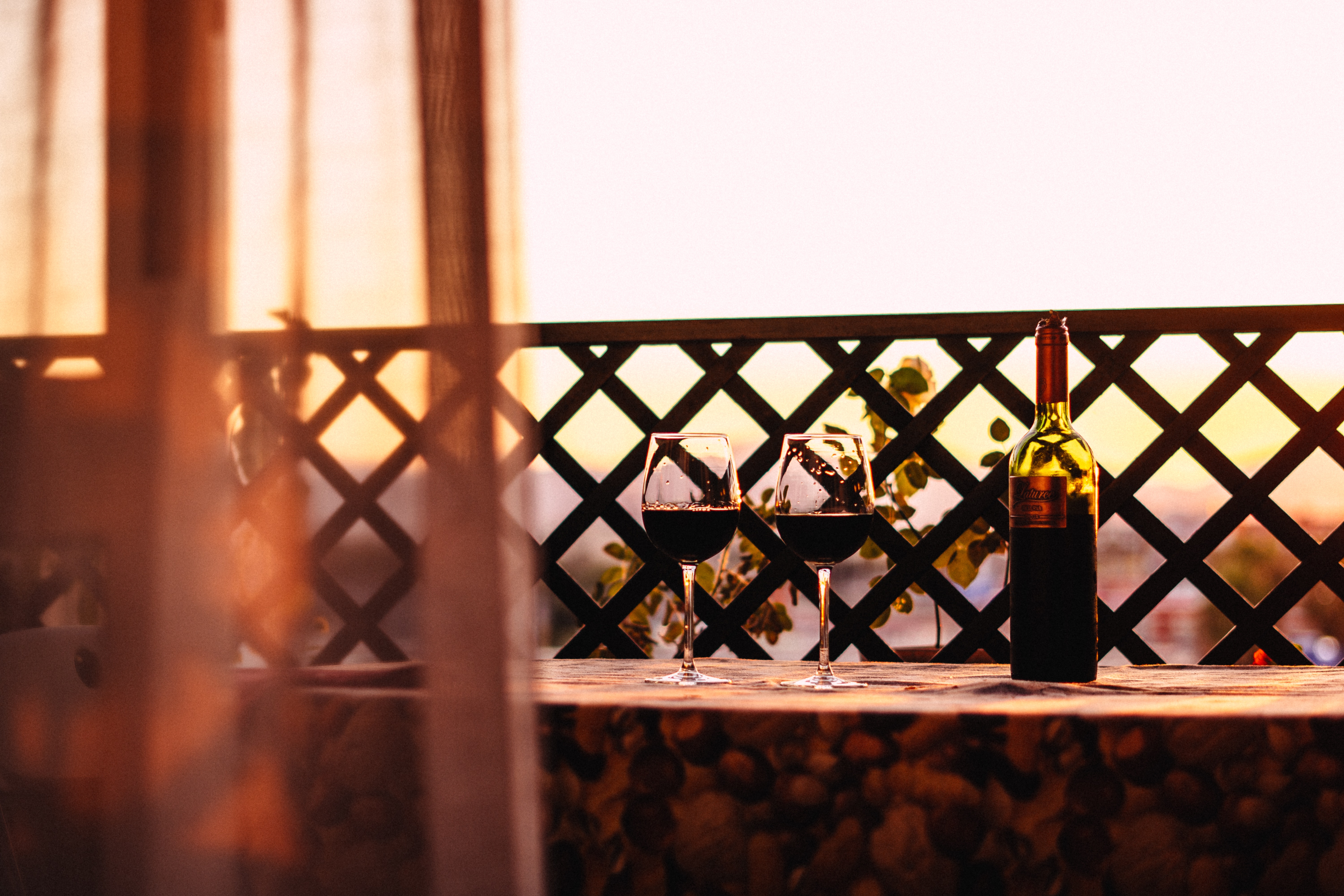 Zwei Rotweingläser auf einem Balkontisch neben einer Weinflasche