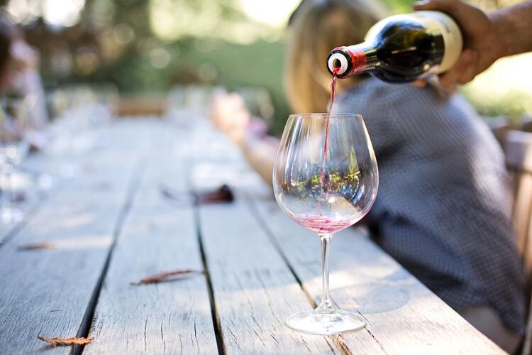 Rotwein wird auf einem Gartentisch in ein Glas gegossen