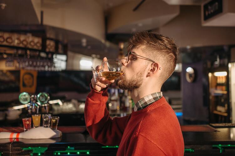 Mann trinkt in einer Bar einen Brandy
