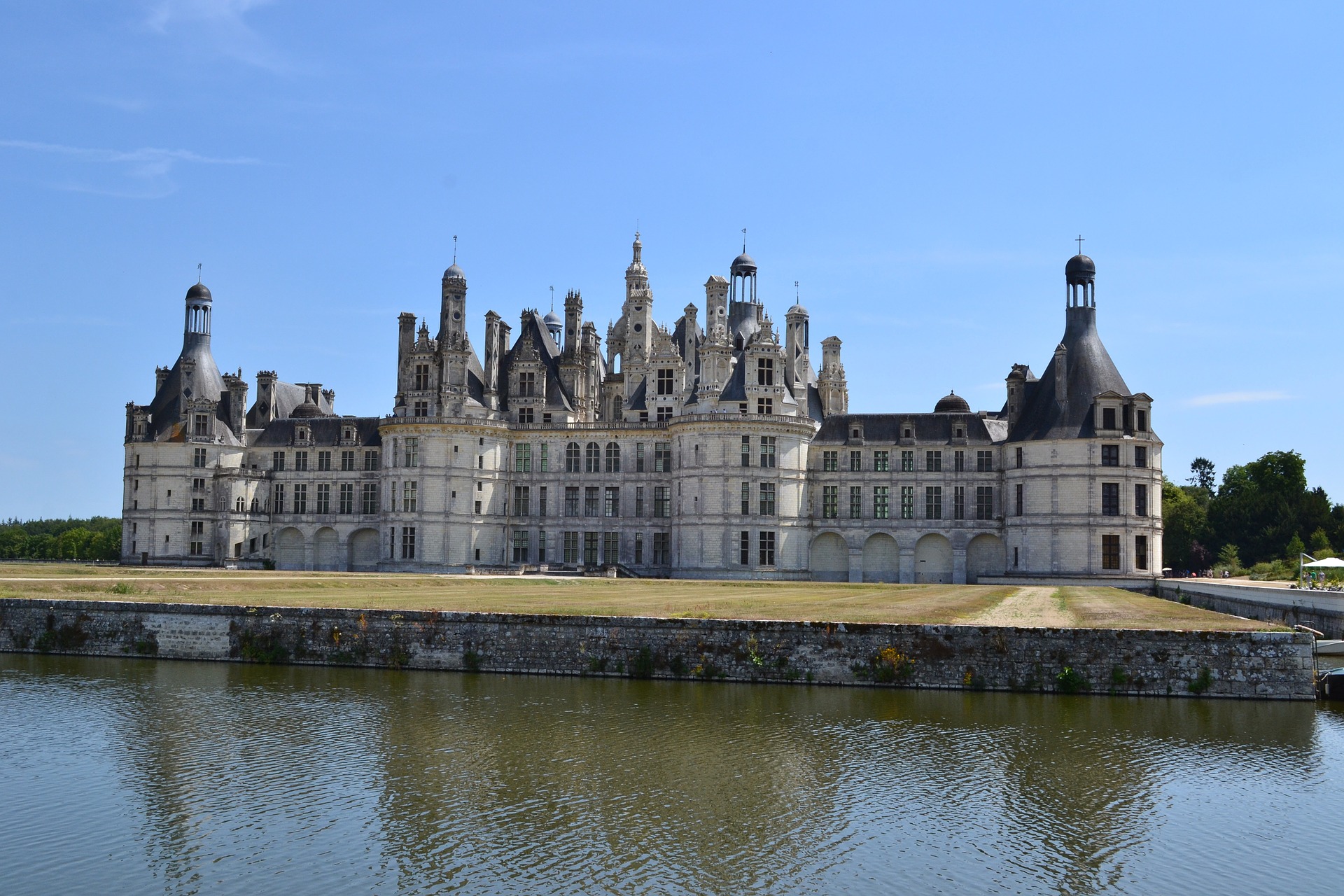 Das Schloss Chambord von außen im Sommer, im Vordergrund ist der französische Fluss Loire zu sehen.