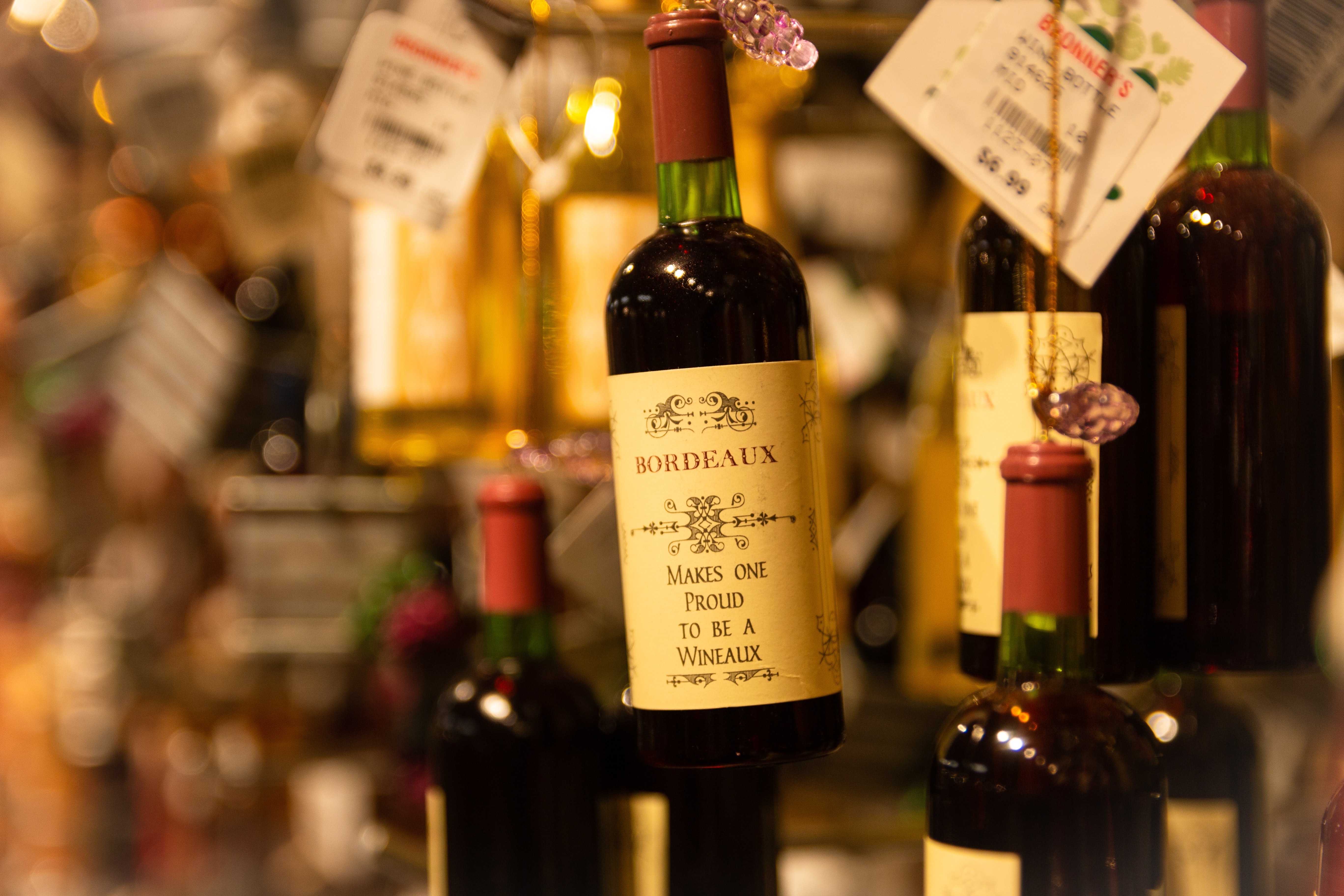 Mehrere Bordeaux-Flaschen hängen zum Verkauf bei dezenter Beleuchtung an Fäden