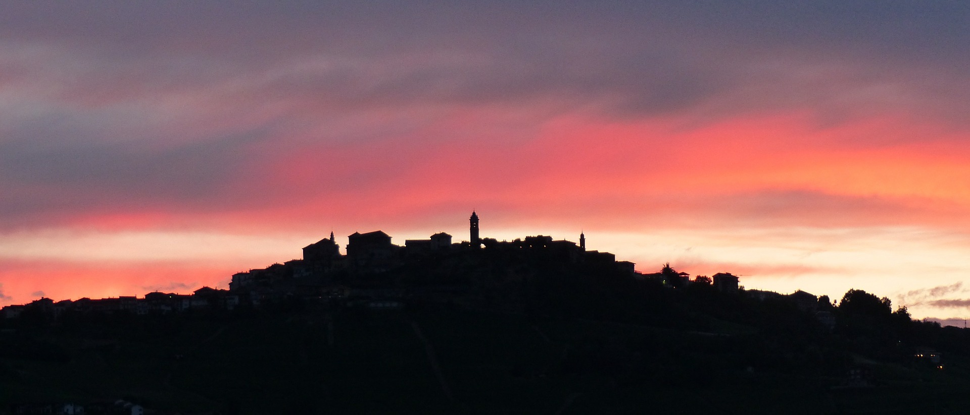 Silhouette eines Bergstädtchens im Piemont vor einem roten Abendhimmel