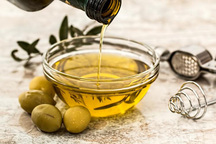 Glasschälchen, das mit Olivenöl gefüllt wird