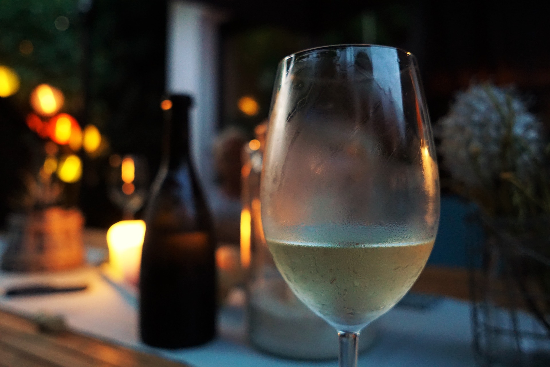 Gekühlter Weißwein auf einem Gartentisch mit Kerze
