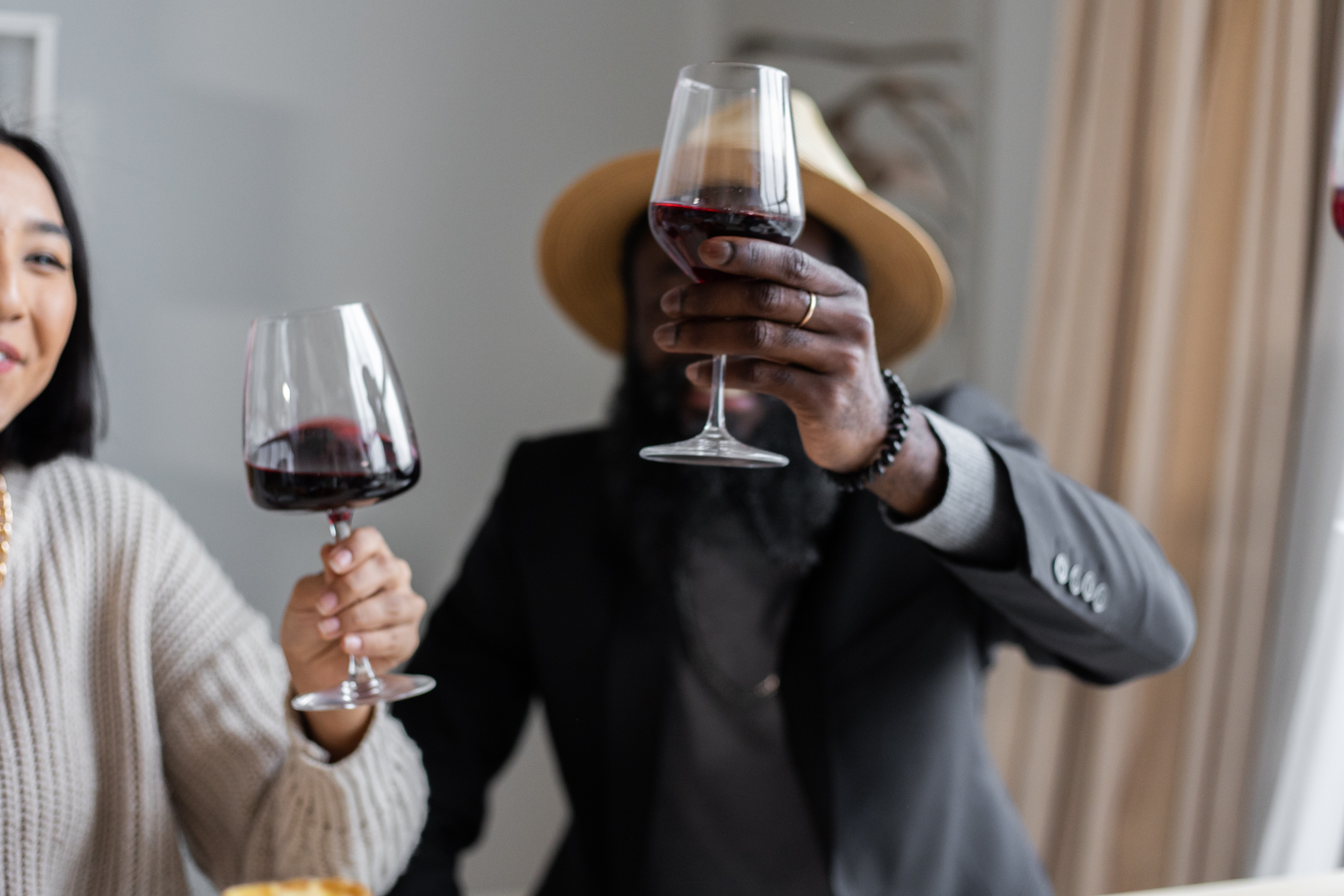 Ein Mann und eine Frau verkosten Wein und betrachten die Weinfarbe im Licht