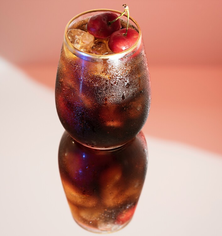 Glas, das mit Sherry gefüllt ist und in dem Eiswürfel und zwei Kirschen liegen