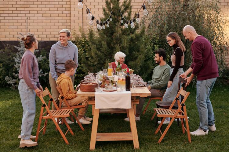 Große Familie kommt an einem gedeckten Tisch unter freiem Himmel zusammen