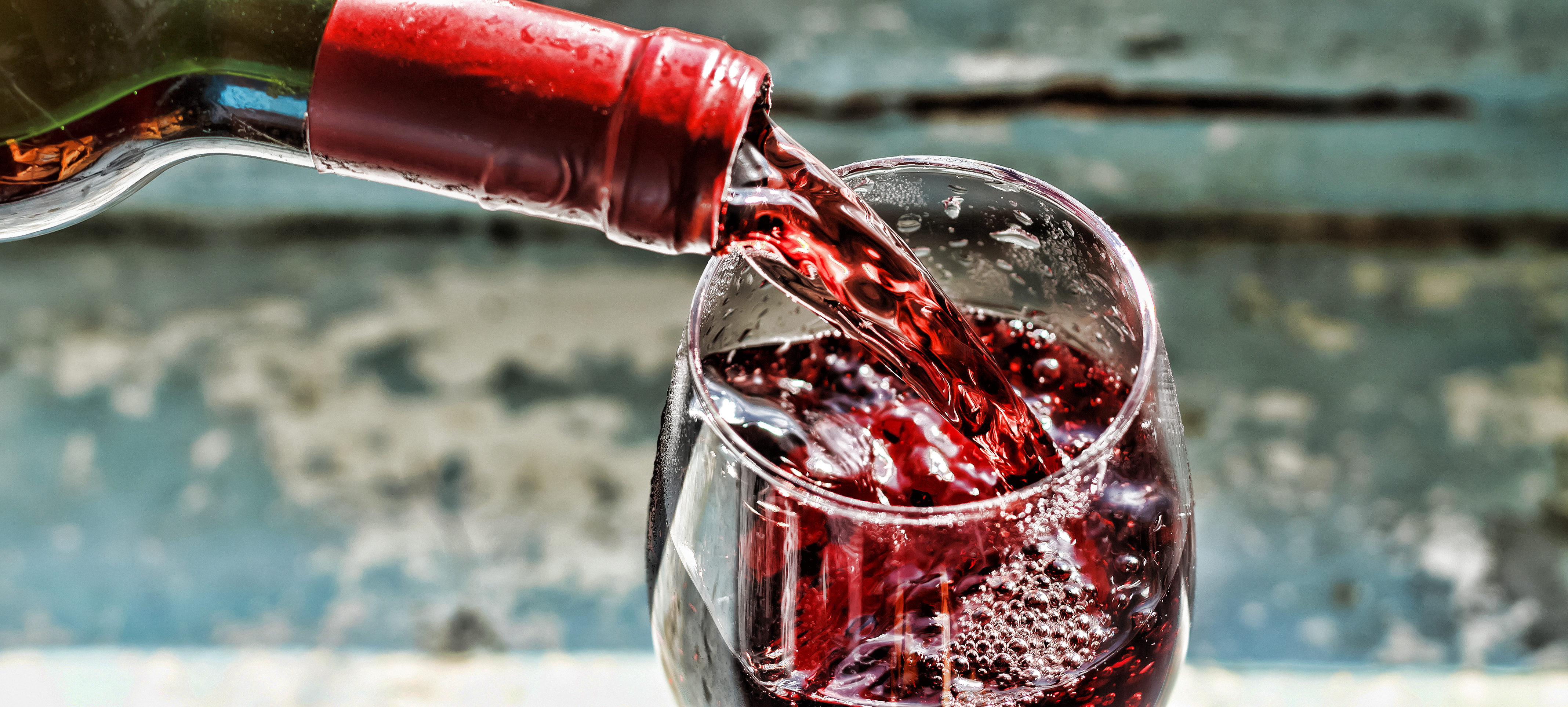 Nahaufnahme eines Rotweinglases, in das Rotwein eingegossen wird